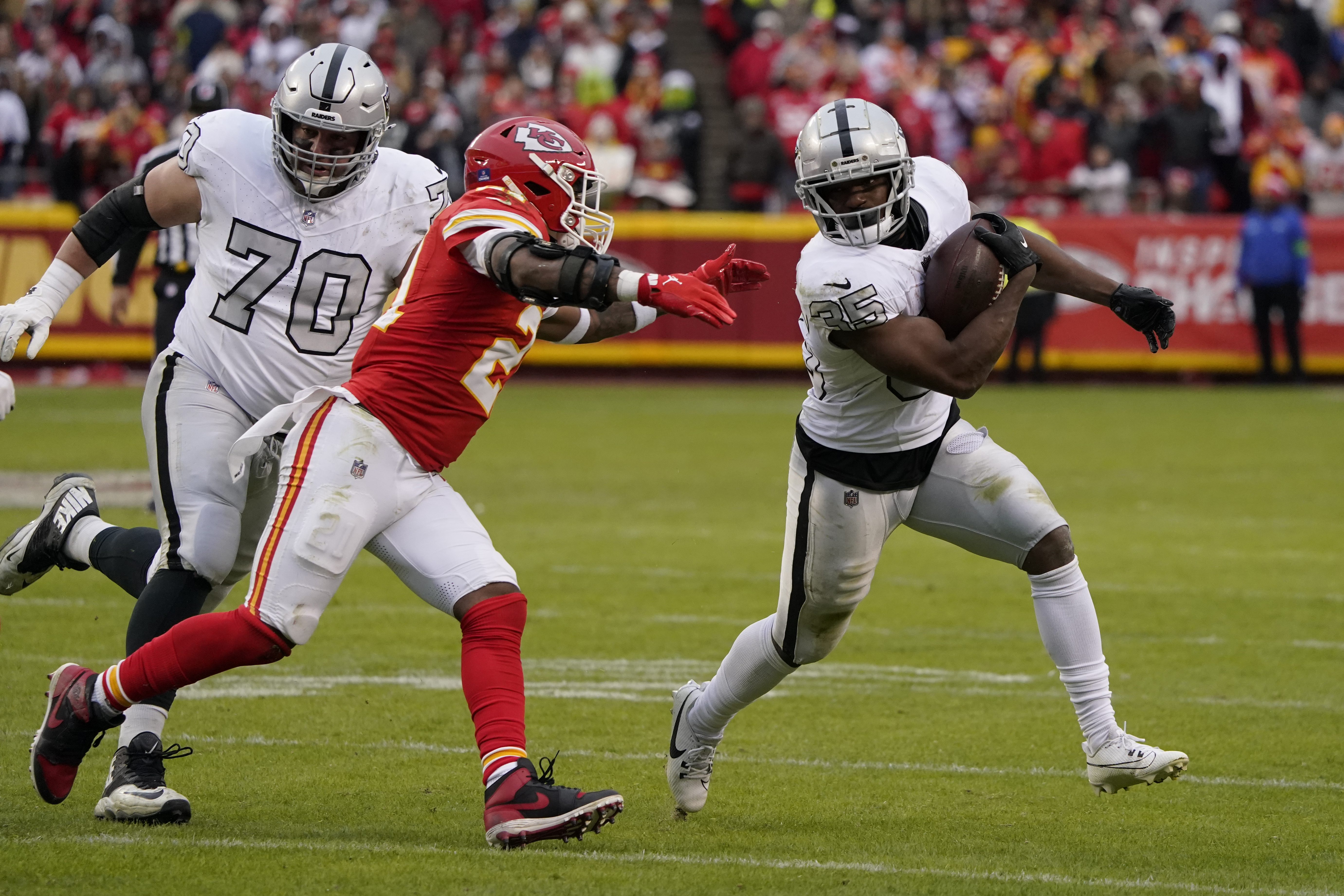 Las Vegas Raiders running back Zamir White (35) runs with the ball as Kansas City Chiefs safety Mike Edwards defends and Raiders guard Greg Van Roten looks on during the second half of an NFL football game Monday, Dec. 25, 2023, in Kansas City, Mo. (AP Photo/Ed Zurga)